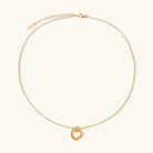 Delicate gold-plated necklace with three interlocking circle rings forming a minimalist knot pendant on cream background