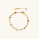 Three-strand gold-plated bracelet with clustered ball beads and adjustable clasp on cream background