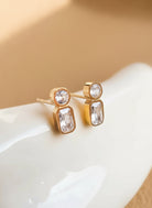 Gold earrings with clear gemstones on a white surface